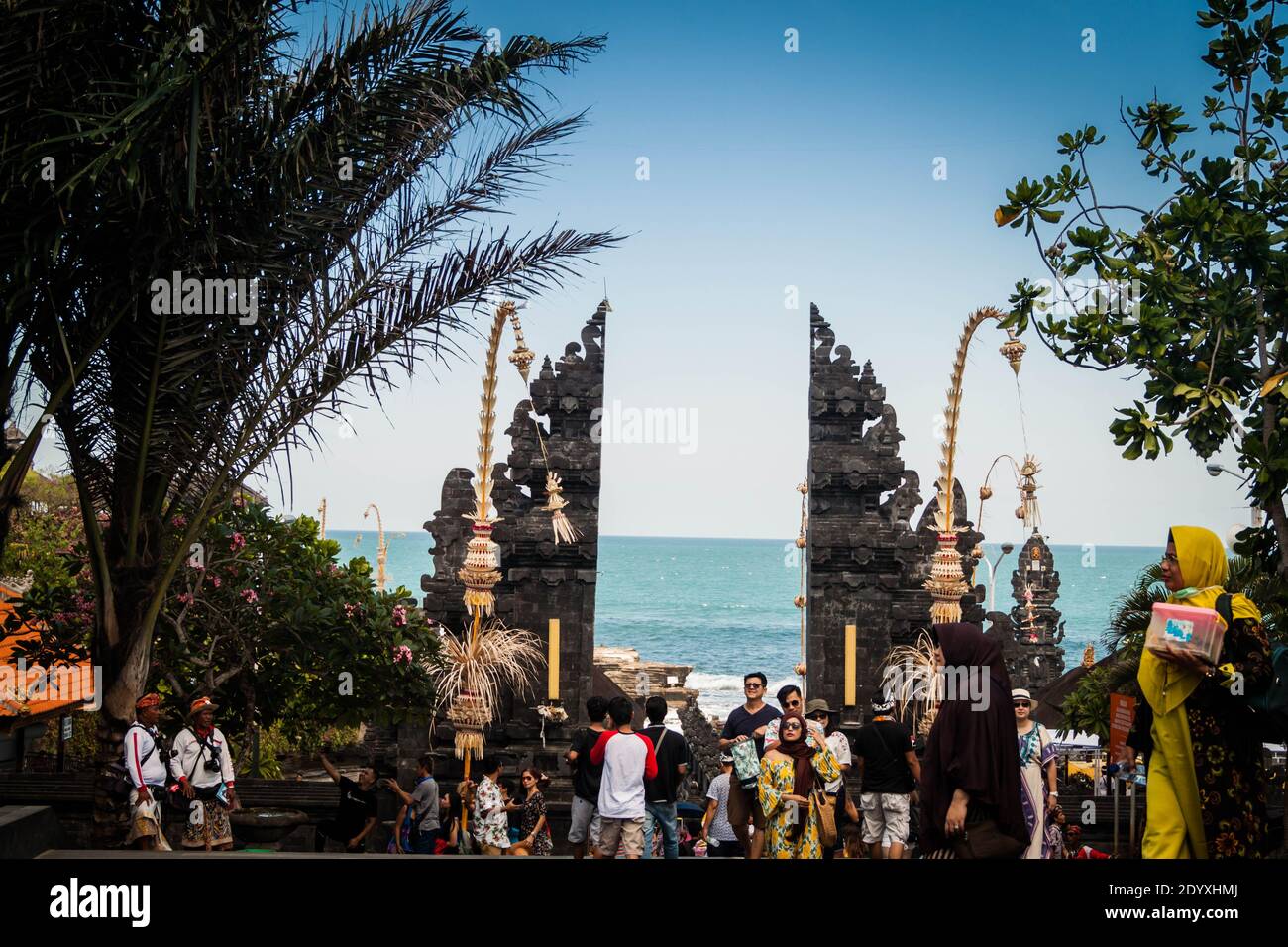 Muslimische und europäische Touristen, die durch den Tanah Lot Tempel spazieren Tor in Bali Stockfoto
