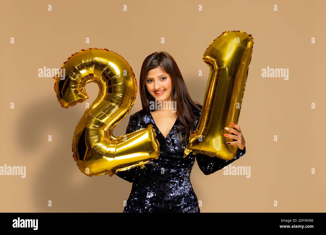 Junge Frau hält 21 goldene Ballons während eines neuen Jahres Party Stockfoto