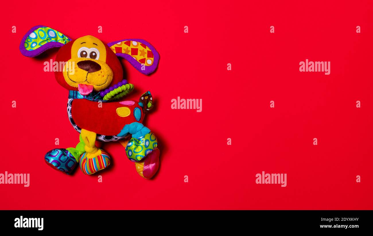 Rot orange doggy Spielzeug auf einem roten Hintergrund mit Kopieplatz für Text. Weiches Plüsch Spielzeug für Baby Hund Banner für Spielzeugladen Stockfoto