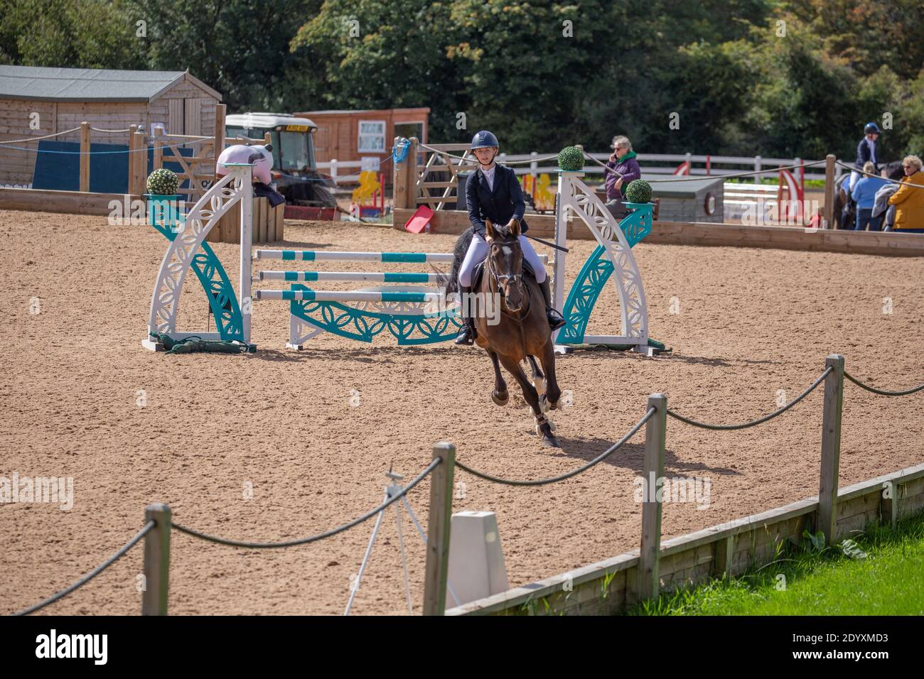 Ein Reiter auf seinem Pferd springt über einen Zaun Sie nehmen an einem lokalen Wettbewerb auf dem Land Teil Stockfoto