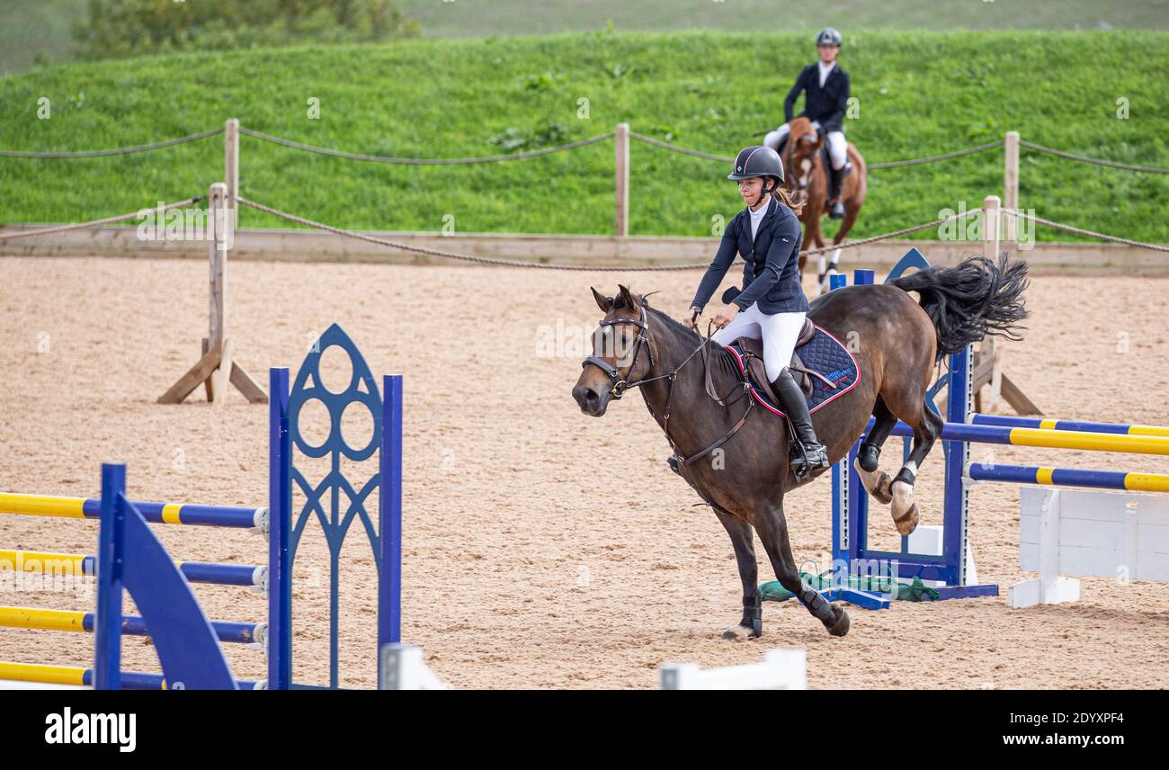 Ein Reiter auf seinem Pferd springt über einen Zaun Sie nehmen an einem lokalen Wettbewerb auf dem Land Teil Stockfoto