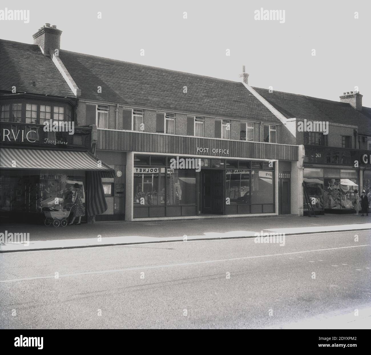 1960er Jahre, historisch, eine britische Hauptstraße mit Außenansicht eines neuen Einzelhandelsgeschäfts für das Post Office, England, Großbritannien. Eine Dame mit einem Kutschenwagen steht im Fenster des Ladens nebenan, eines Schuhgeschäfts oder eines Schuhgeschäfts, das in dieser Zeit genannt wurde, eines Fußmacher-Ladens. Stockfoto