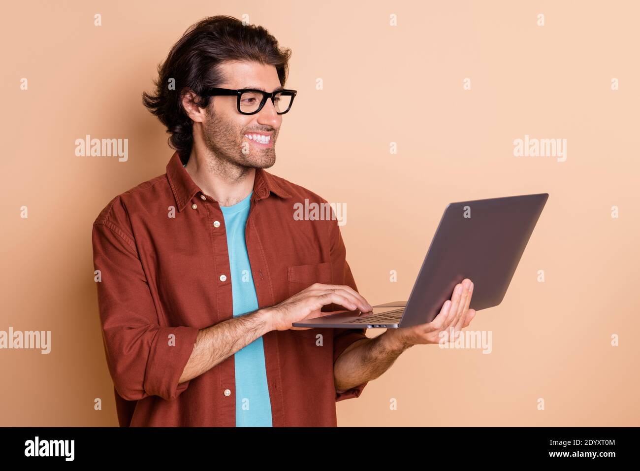 Foto Porträt von Mann hält Laptop in der Hand tippen isoliert Auf pastellbeigefarbenem Hintergrund Stockfoto