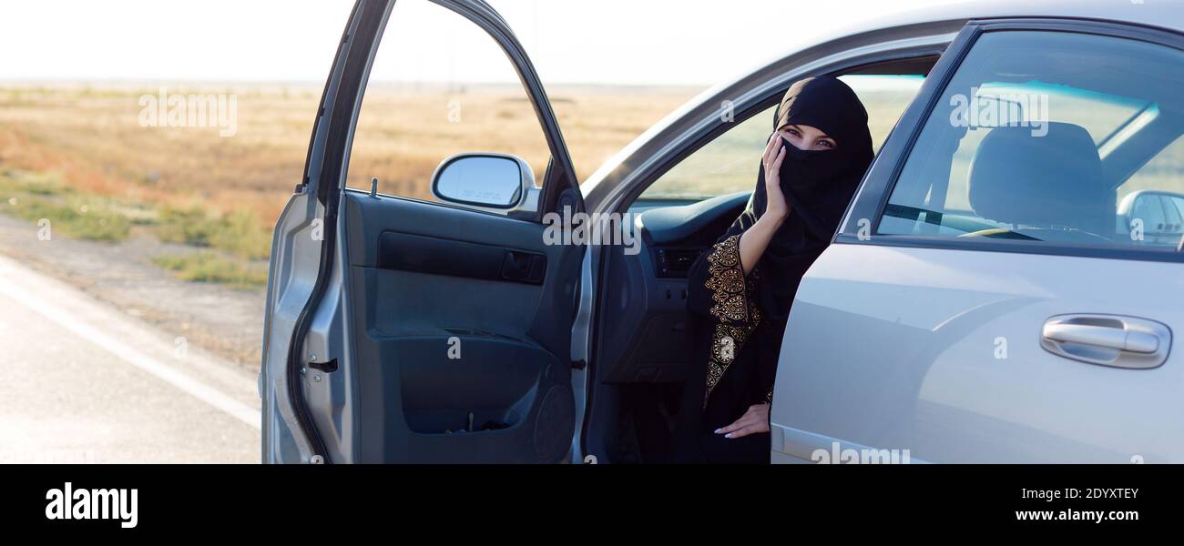 Islamische Frau, die im Auto sitzt und die Eingangstür weit geöffnet hat. Stockfoto