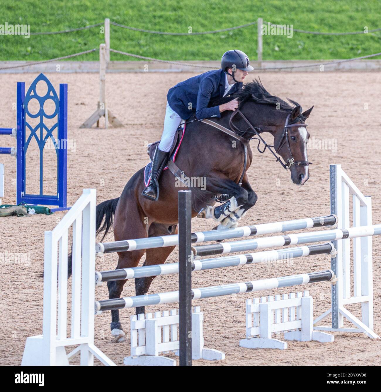 Ein Reiter auf seinem Pferd springt über einen Zaun Sie nehmen an einem lokalen Wettbewerb auf dem Land Teil Stockfoto