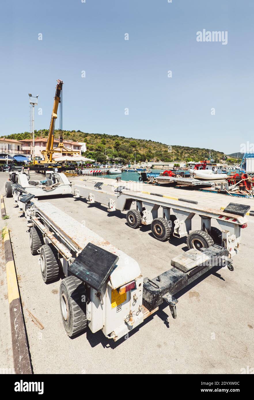 Gelber Teleskopkran und grauer Schwerlasttransporter für Boote und Yachten im Hafen von Talamone, Toskana, Italien Stockfoto