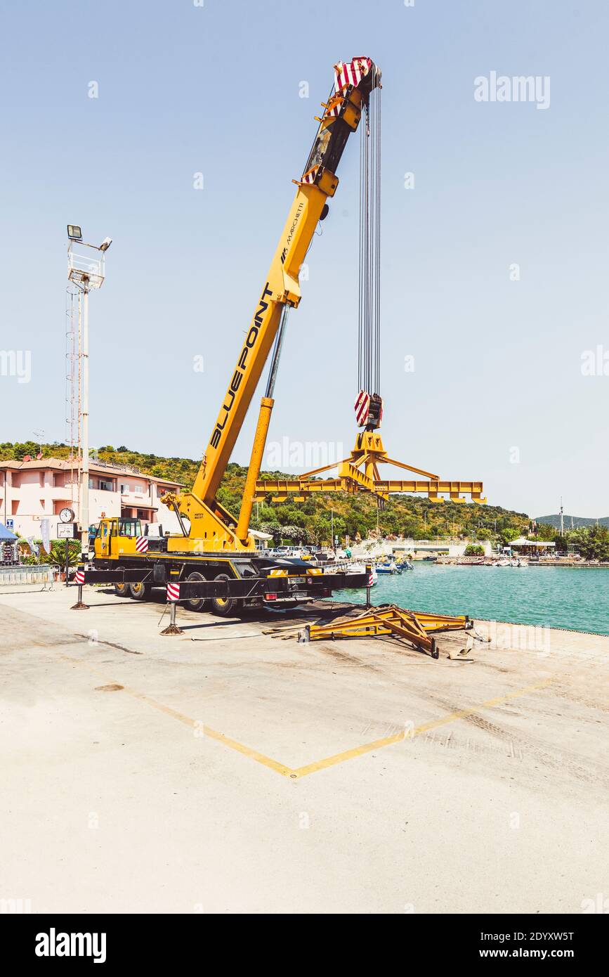Gelber Teleskopkran-LKW für Boote und Yachten mit Querbalken an einer Anlegestelle im Hafen von Talamone, Toskana, Italien Stockfoto