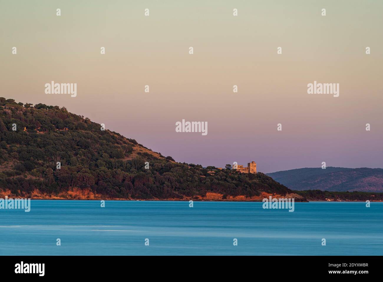 Der Festungsturm Torre di Talamonaccio an der Bucht von Talamone leuchtet in der Abenddämmerung in der Dämmerung, Toskana, Italien Stockfoto