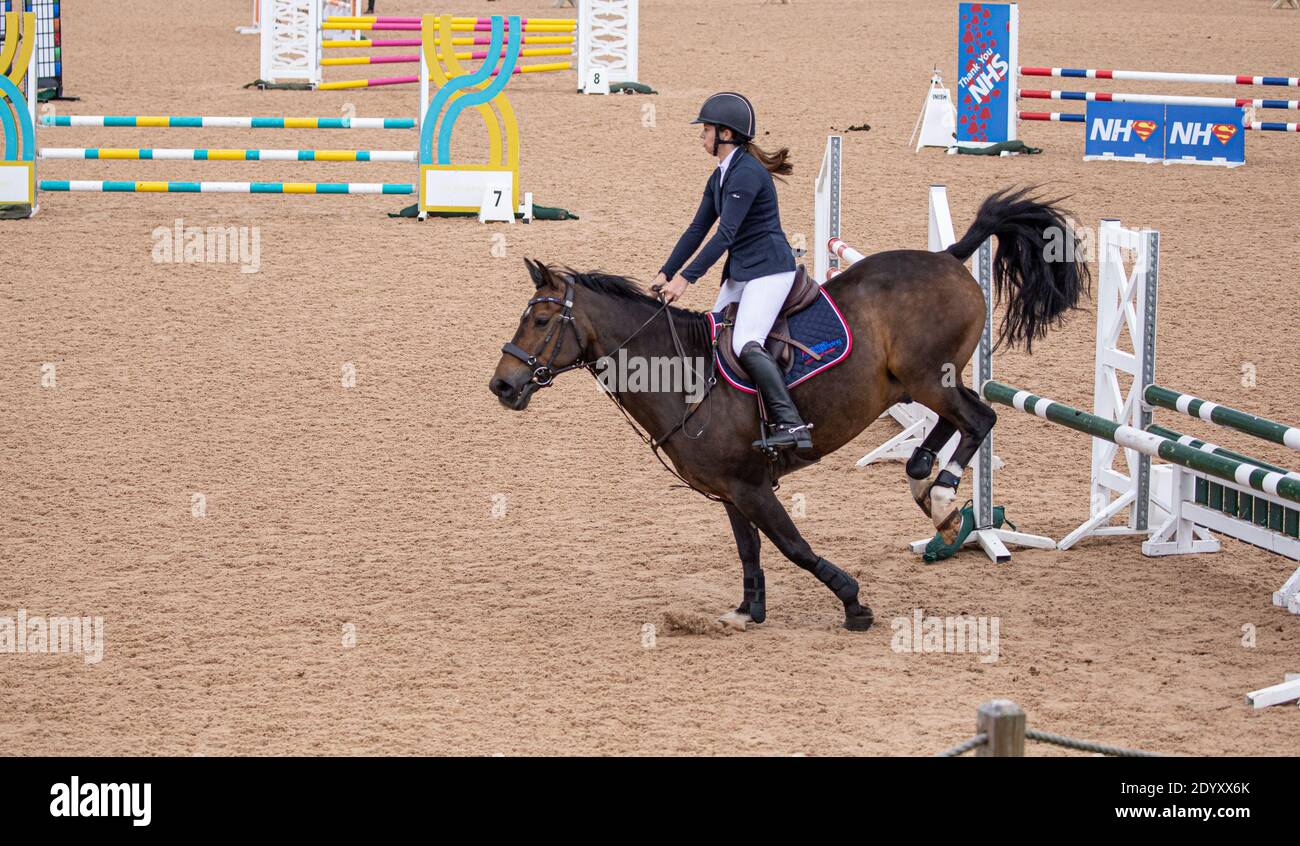 Ein Reiter auf seinem Pferd springt über einen Zaun Sie nehmen an einem lokalen Wettbewerb auf dem Land Teil Stockfoto