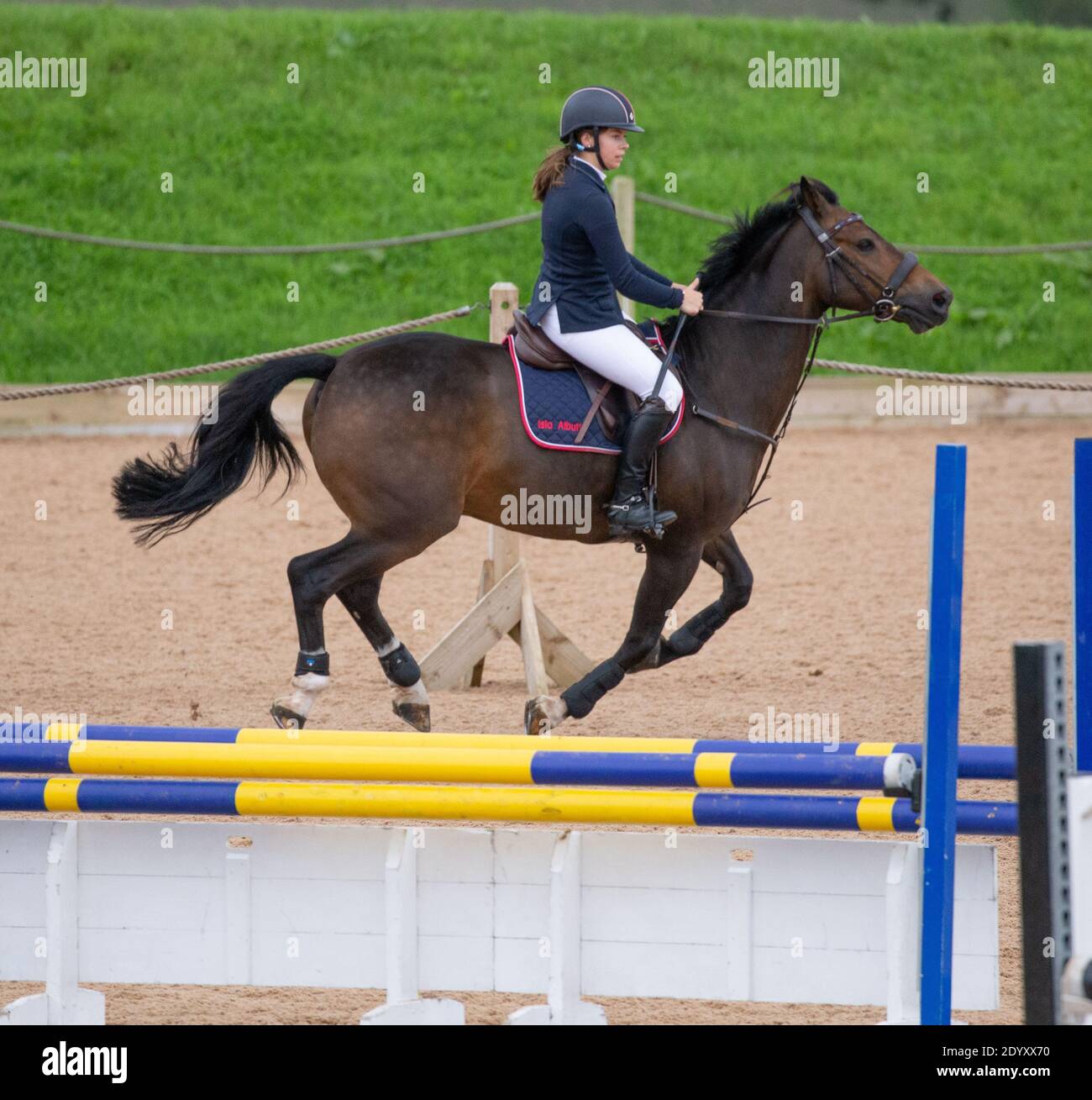 Ein Reiter auf seinem Pferd springt über einen Zaun Sie nehmen an einem lokalen Wettbewerb auf dem Land Teil Stockfoto
