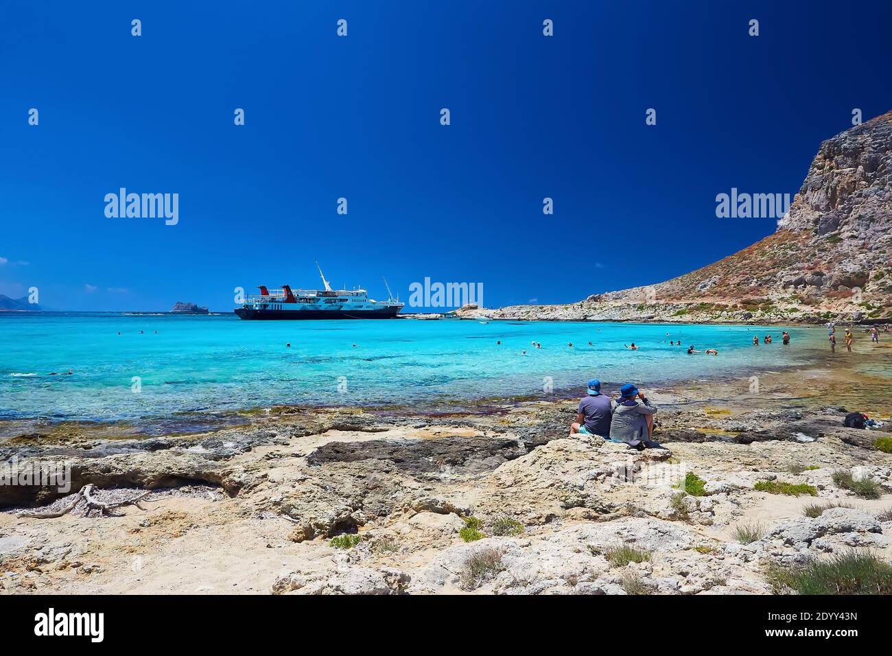 2019, 4. JUNI: - GRIECHENLAND, DIE INSEL KRETA, BALOS - die Burg auf dem Gipfel des Berges und die Menschen am Strand darunter. Stockfoto