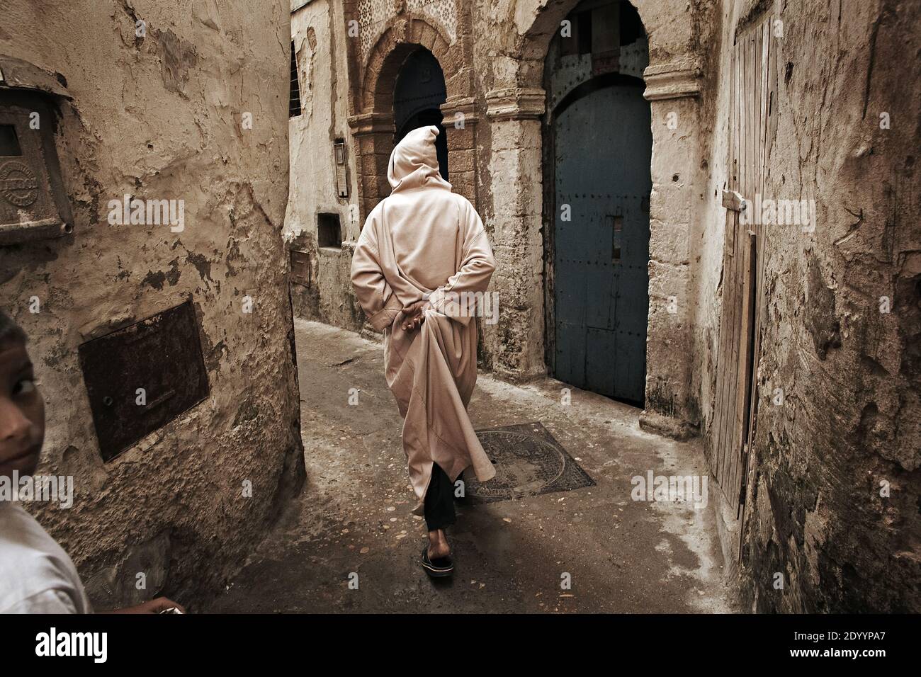 MAROKKO / Essaouira / traditionell gekleideter Mann bei einem Spaziergang in einer typischen schmalen Streette der Medina (Altstadt) in Essaouira. Stockfoto