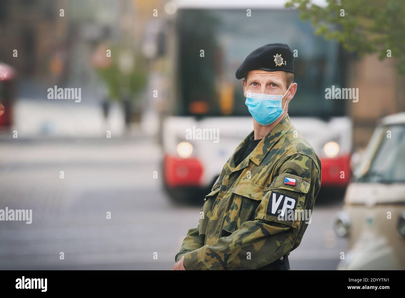 Ein Mitglied der tschechischen Militärpolizei mit einer Gesichtsmaske (OP-Tuch), die auf einer Stadtstraße steht. Stockfoto