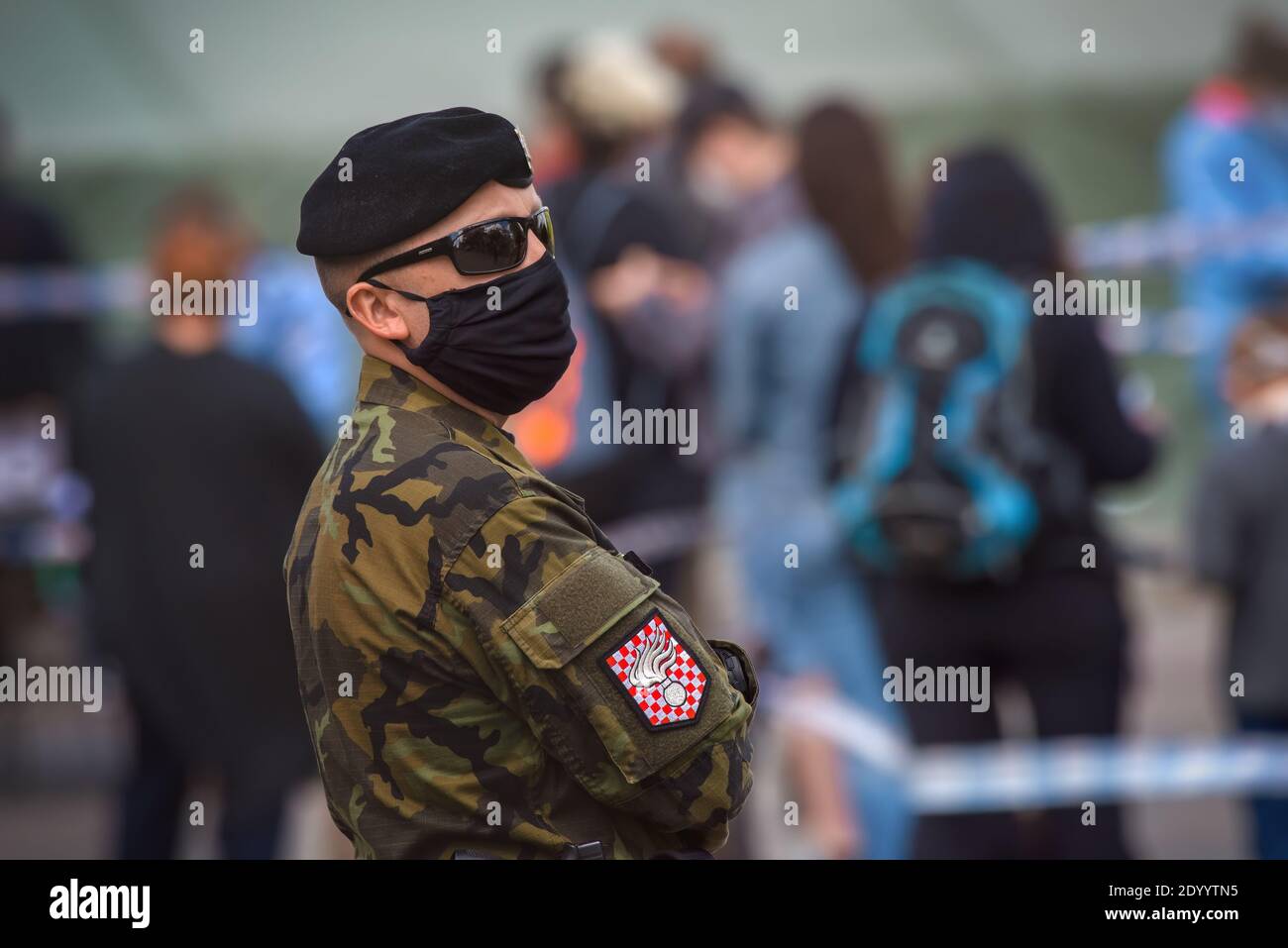 Ein Mitglied der tschechischen Militärpolizei mit einer Stoffmaske, die auf der Straße an einer Schlange von Menschen steht, die auf einen Corona-Virus-Test warten. Stockfoto