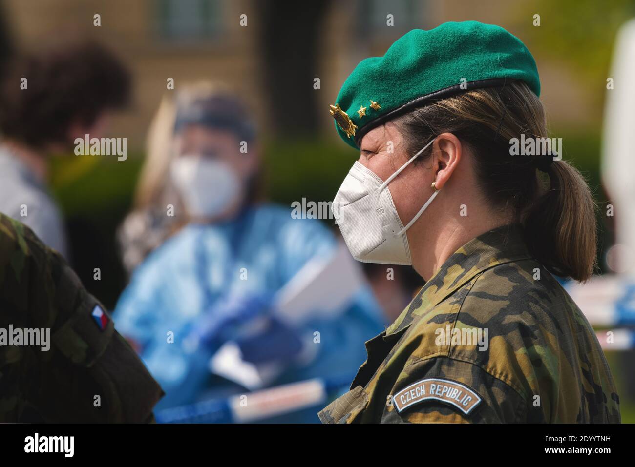 Ein Mitglied der tschechischen Militärpolizei mit einem Atemschutzgerät, das auf der Straße in einer Schlange von Menschen steht, die auf einen Corona-Virus-Test warten. Stockfoto