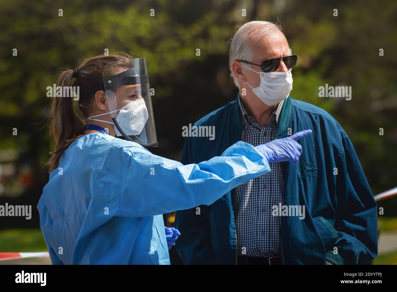 Medic zeigt den alten Mann mit Stoffmaske auf den Ort, an dem die kollektiven Immunitätstests gegen das Corona-Virus stattfinden. Stockfoto
