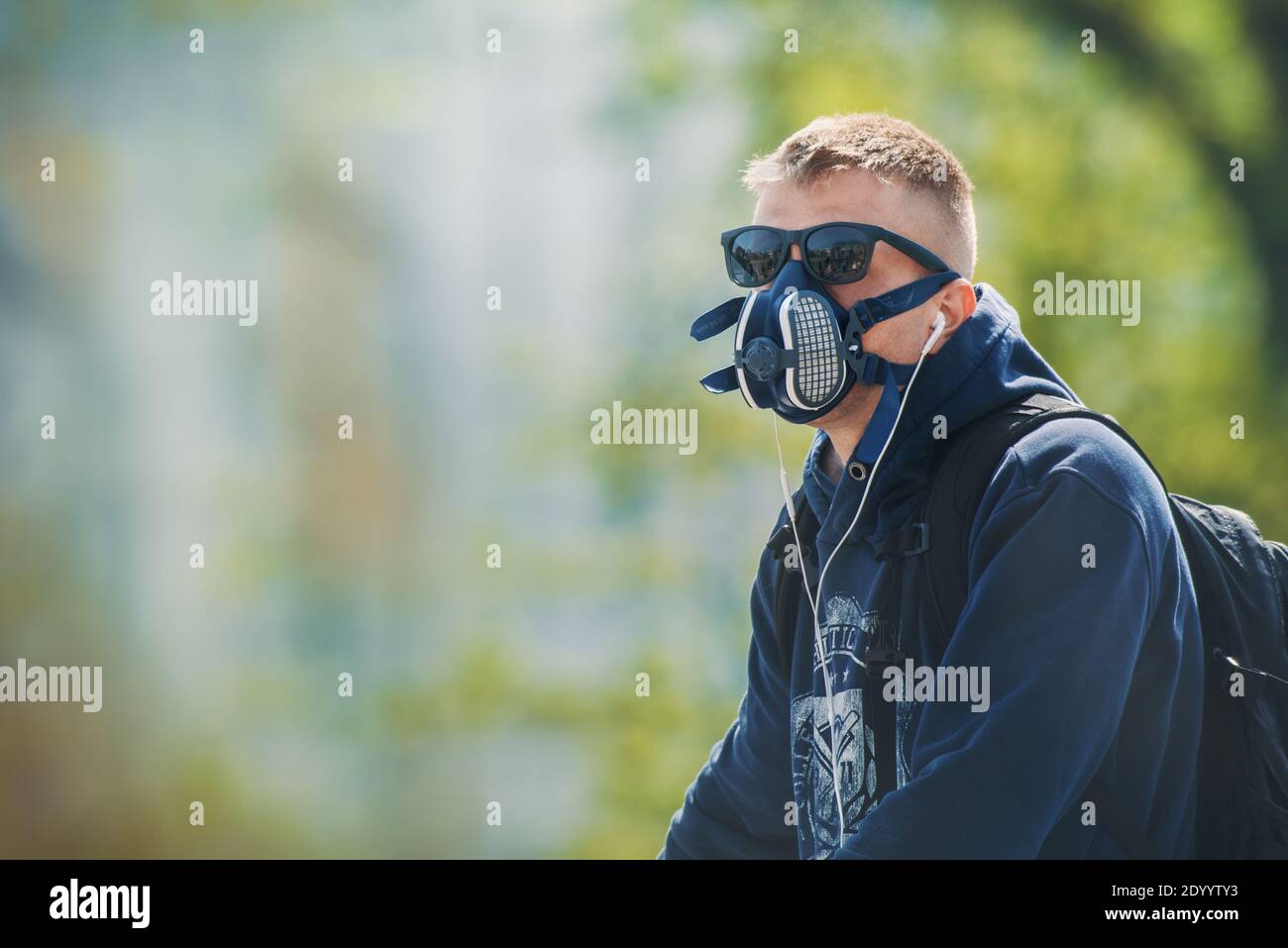Der junge Mann trägt eine N99 Atemschutzmaske und Sonnenbrille. Der Mann schützt sich vor Coronavirus und anderen luftgetragenen Partikeln und Krankheiten. Stockfoto