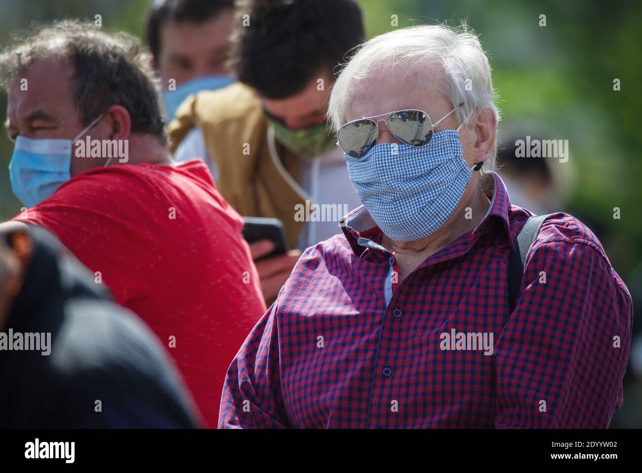 Nahaufnahme eines alten Mannes mit einer Stoffmaske, die in Menschenanschlange auf einen kollektiven Immunitätstest gegen den Corona-Virus wartet. Stockfoto