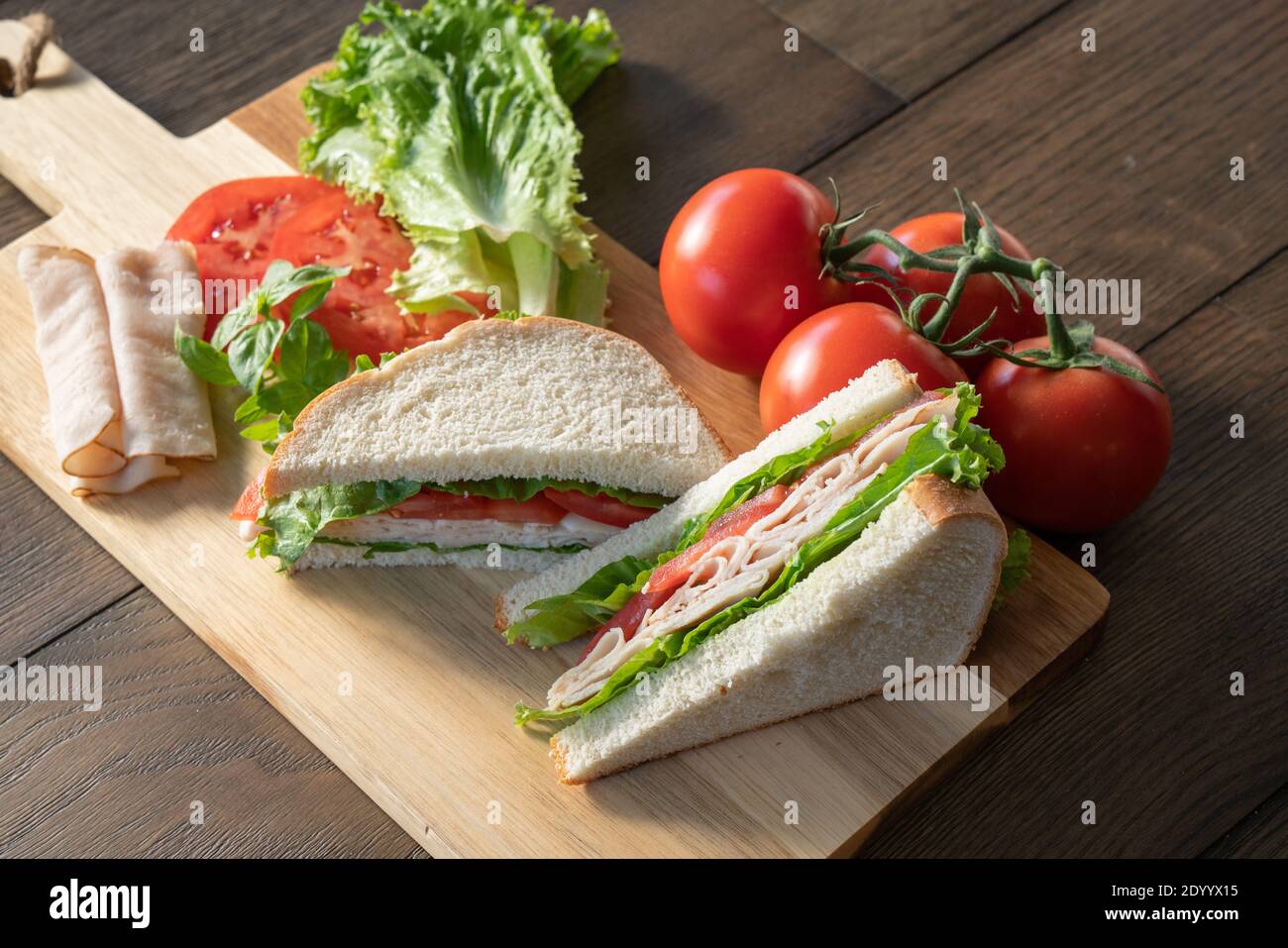 Frischer truthahn, Salat und Tomatenbrot, halbiert auf Schneidebrett Stockfoto