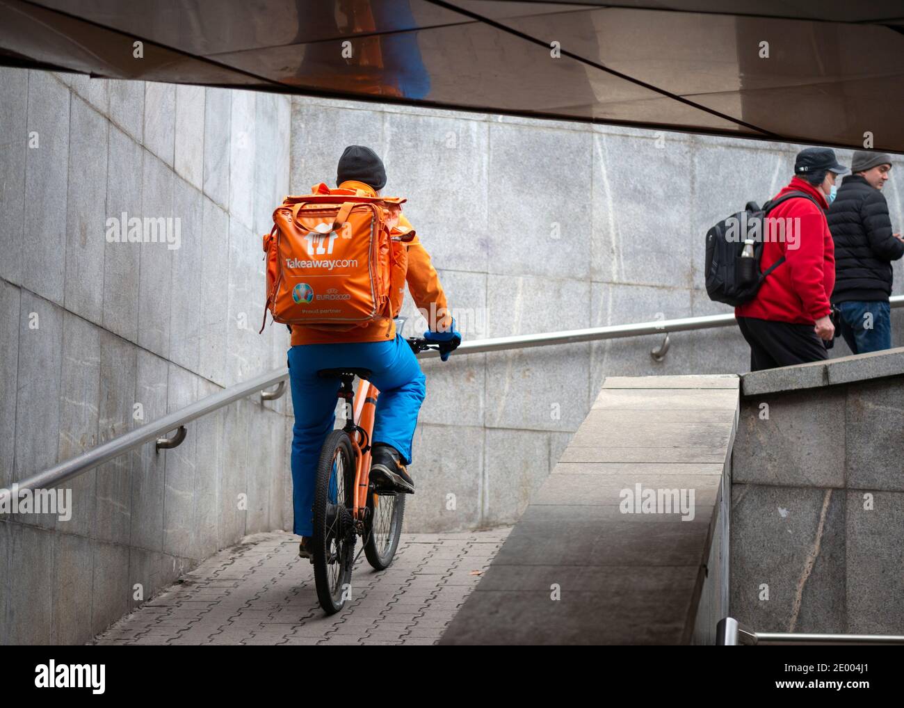 Takeaway Fast-Food-Lieferung männlichen Radfahrer Kurier trägt die Firma Orange Outfit mit Fahrrad Radfahren unter den Menschen in Unterführung in Sofia Bulgarien Stockfoto