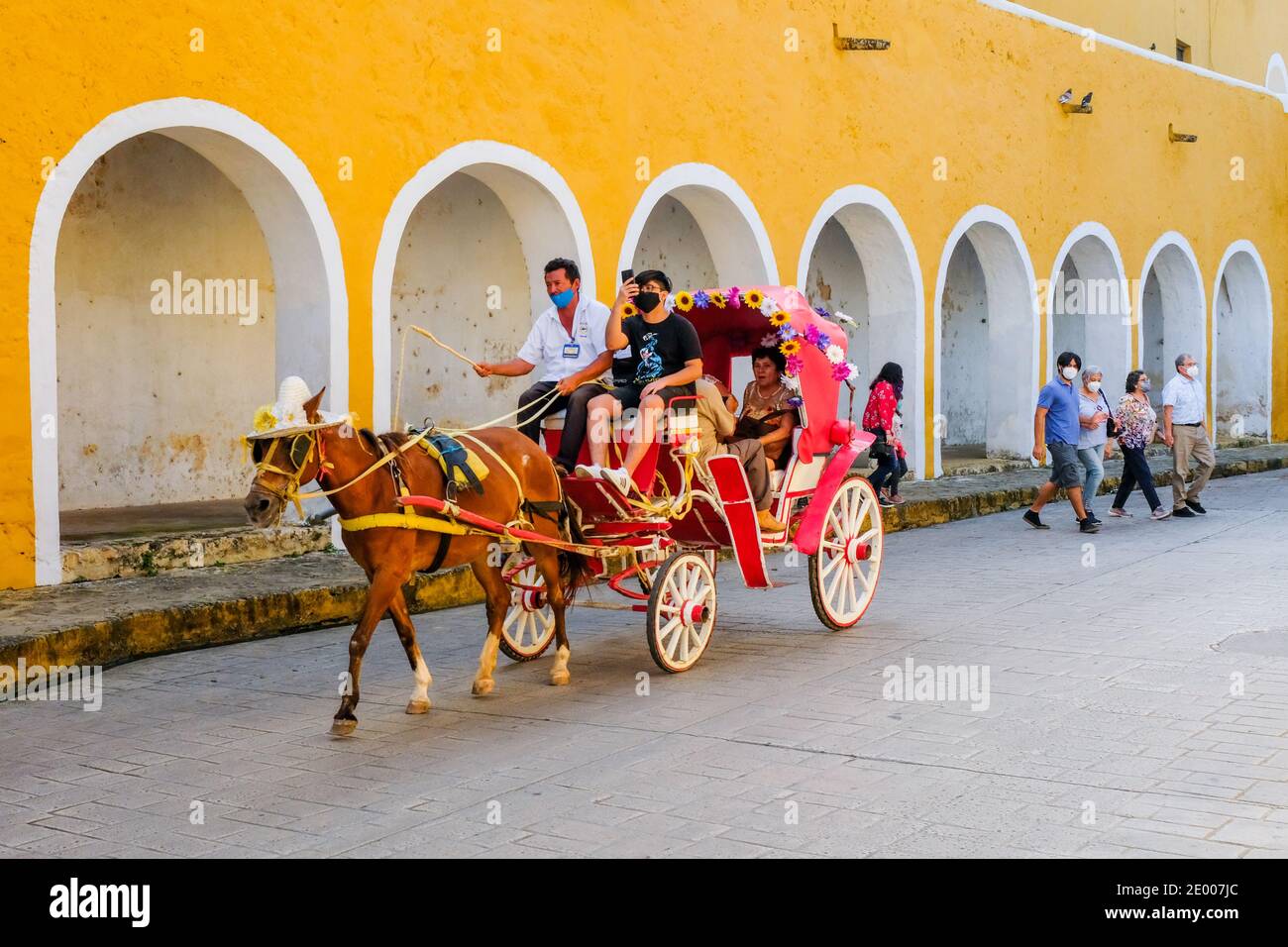 Touristen, die während der Pandemie Covid-19 die historische Stadt Izamal, Mexiko, in einer Pferdekutsche besichtigen Stockfoto