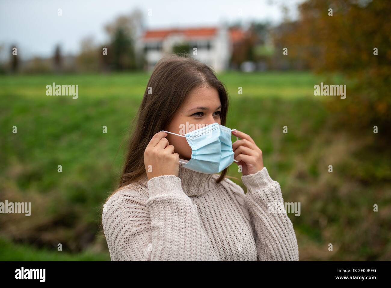 Junge Frau im Park trägt Schutzmaske während Pandemie covid-19, Herbstsaison Stockfoto