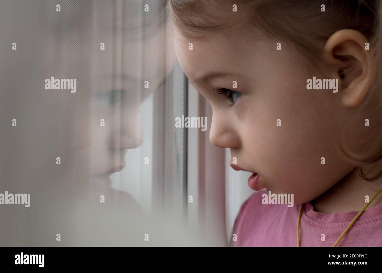 Kindheit, Einsamkeit, Isolation, Traurigkeit, Hoffnung Konzepte - eine traurige niedlich besorgt Kleinkind Baby Mädchen in rosa mit Pferdeschwänze Frisur schaut durch Stockfoto