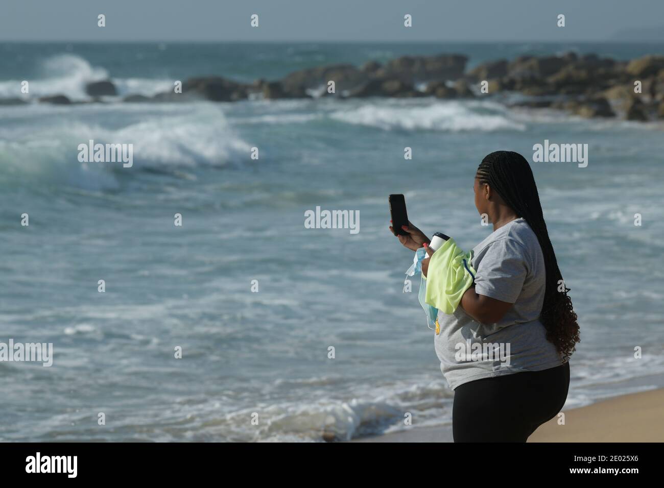 Menschen, alleinerziehende Frau, die ein Handy-Foto am schönen Strand macht, Badeurlaub, Durban, KwaZulu-Natal, Südafrika, lokaler Tourist Stockfoto