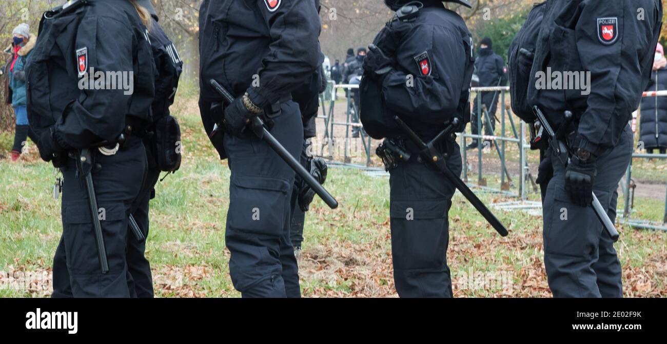 Braunschweig, 05. Dezember 2020: Vier deutsche Polizeibeamte in schwarzen Uniformen mit Knüppeln stehen in einer Schlange. Stockfoto
