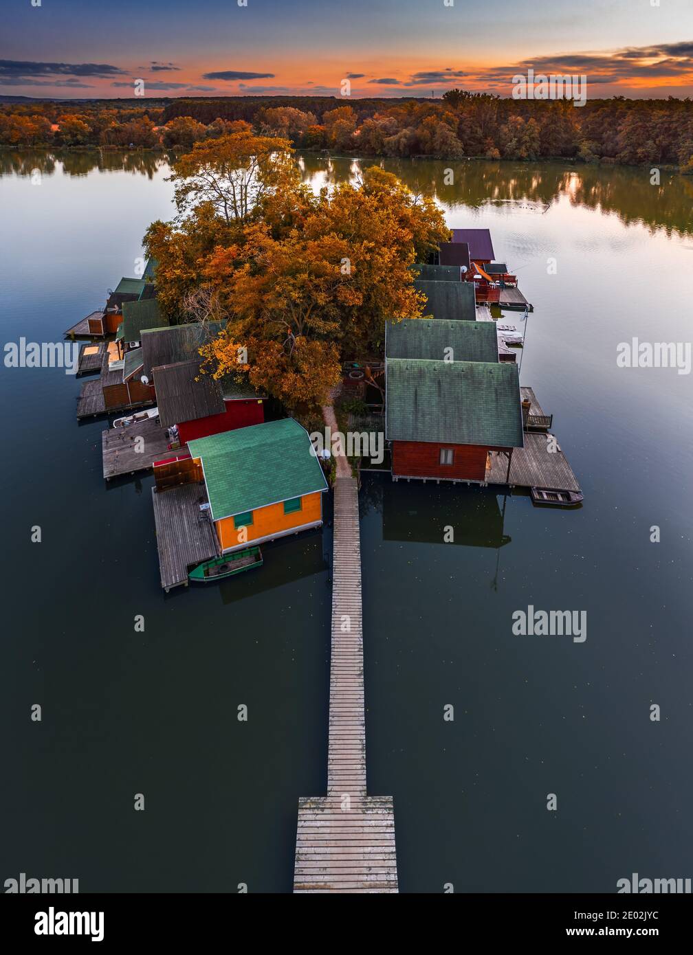 Tata, Ungarn - Luftaufnahme eines wunderschönen Herbstuntergangs über hölzernen Fischerhütten auf einer kleinen Insel am Derito-See (Derito-to). Der See kann foun sein Stockfoto
