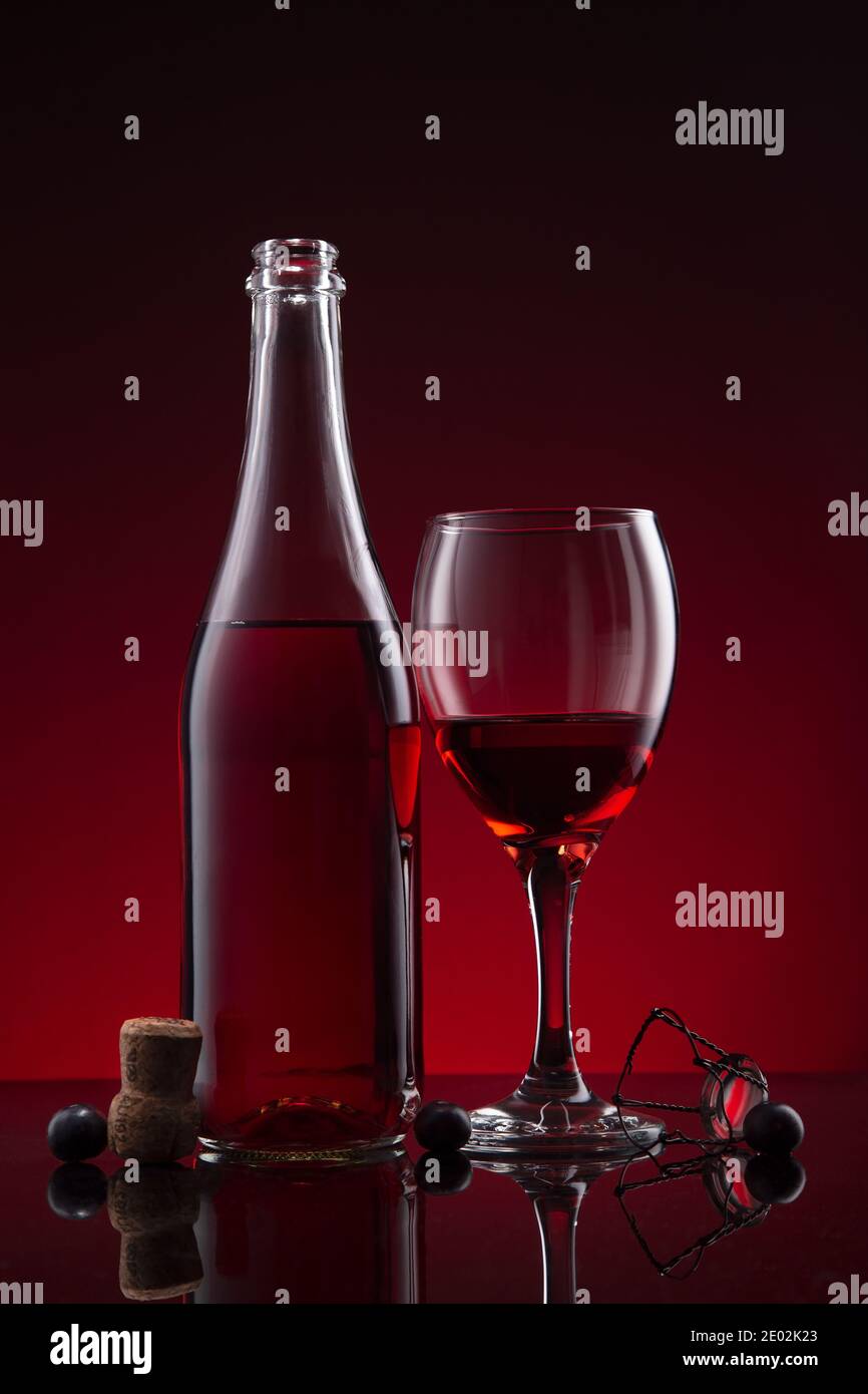 Flasche und Glas Lambrusco Wein auf rot dunklem Hintergrund. Stockfoto