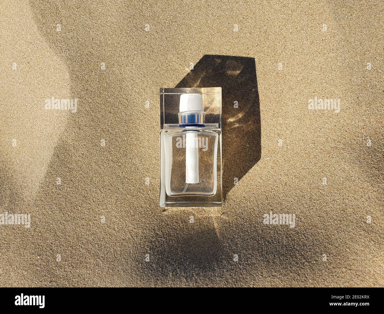 Weiße Parfüm Glasflasche auf sauberem Strandsand mit trendigen Schatten. Draufsicht, Mockup. Stockfoto