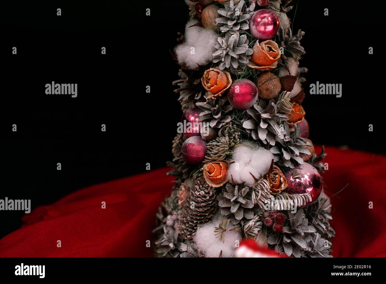 Handgefertigter Weihnachtsbaum mit Zapfen und rosa Weihnachtskugeln Dunkler Hintergrund Stockfoto