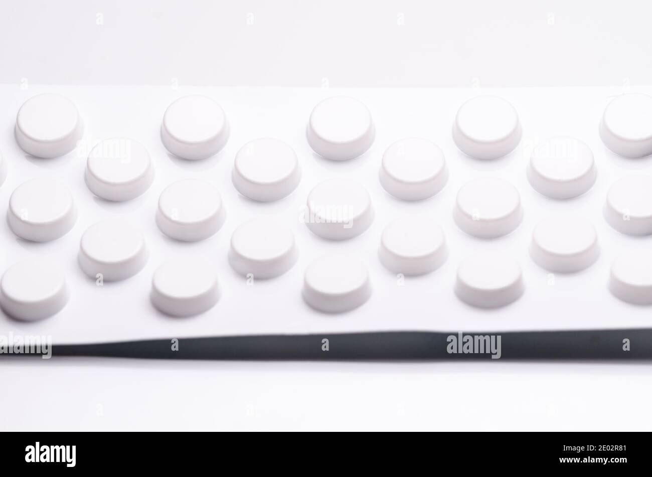 Weiße Pillen oder Tabletten auf weißem Hintergrund, Blisterpackung, Nahaufnahme Stillleben, High-Key-Beleuchtung, flach legen, Apotheke, Medikamente oder Medizin-Konzept Stockfoto