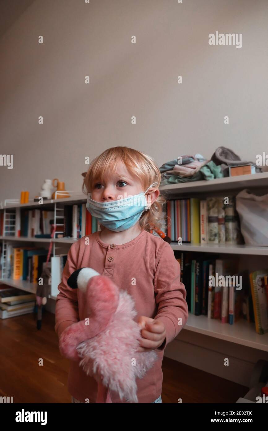 Kind trägt Gesichtsmaske unter der Nase zu Hause. Mittlere Aufnahme. Stockfoto