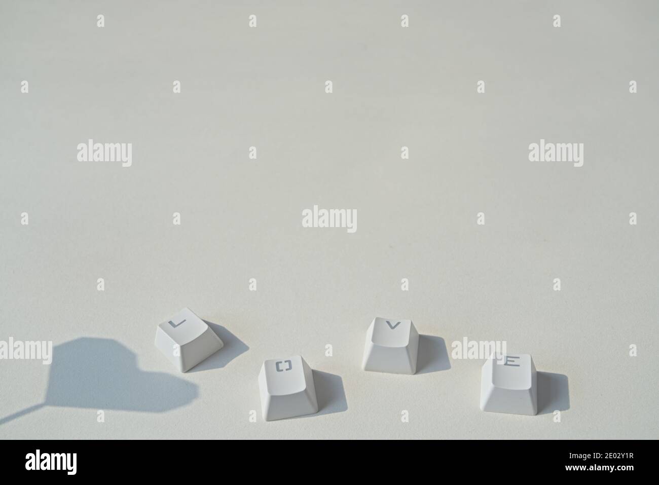 Liebeswort bestehend aus Tastaturtasten, herzförmiger Schatten auf grauem Hintergrund Stockfoto