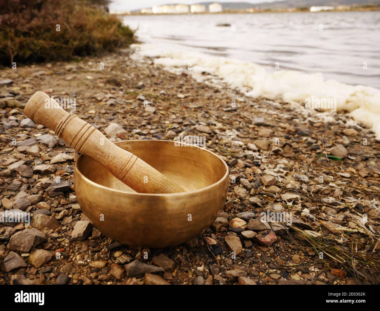 Singende Schüssel auf einem Kiesstrand mit dem Meer gesetzt Im Hintergrund Stockfoto