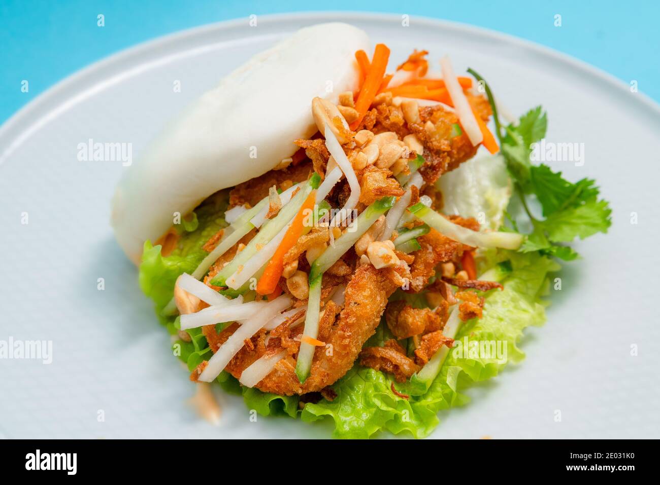 Köstliches gedämpftes bao-Brötchen auf einem Teller mit gebratenem Huhn und frischem Gemüse - Salat, Karotten und gerösteten Erdnüssen. Beliebtes Street Food Stockfoto