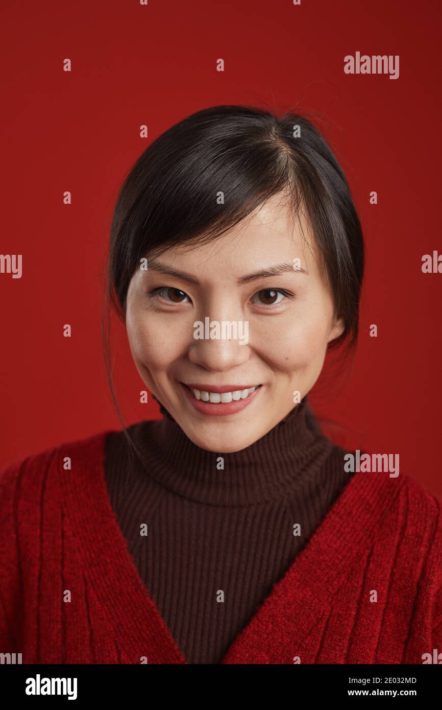 Nahaufnahme Studio Porträt der schönen reifen chinesischen Frau lächelt an der Kamera, roter Hintergrund Stockfoto