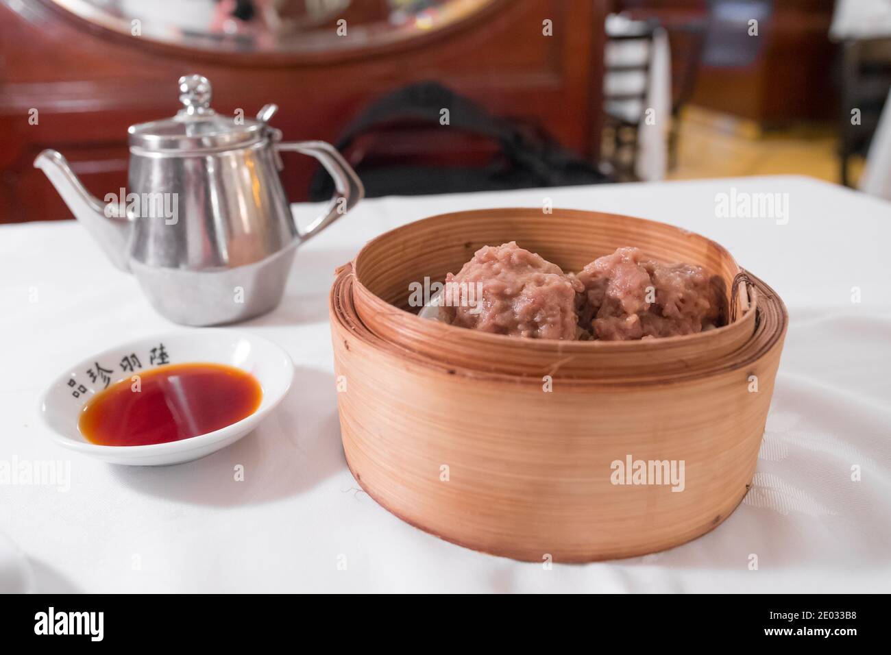 Tee & Dim Sum auf einem weißen Tisch : Eisenkessel, Dim Sum bambou Korb gedünstetes Rindfleisch Bälle. Trinken und Essen. Stockfoto