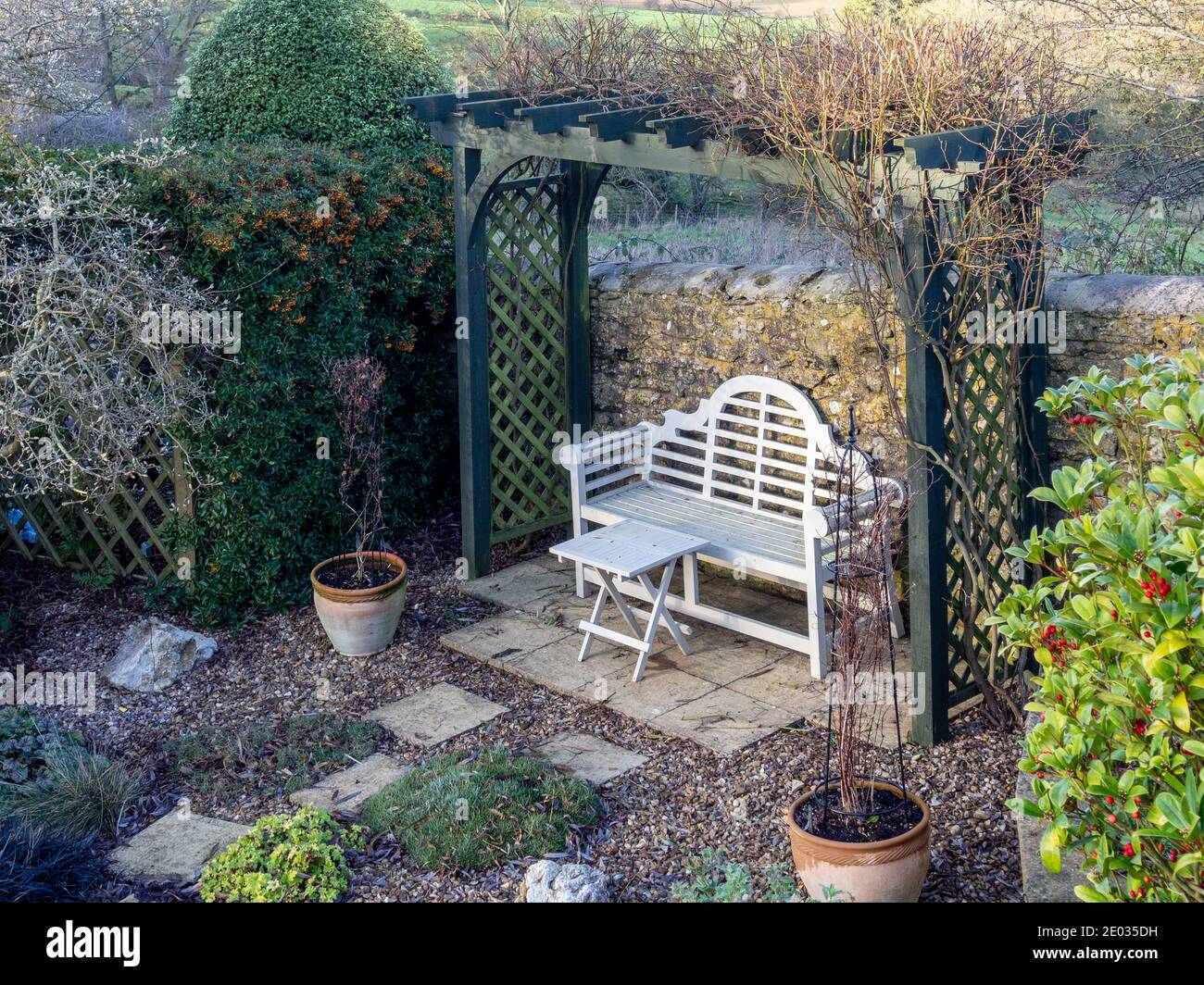 Ein englischer Garten im Winter mit Laube und weißer Bank, Gayton, Northamptonshire, Großbritannien Stockfoto