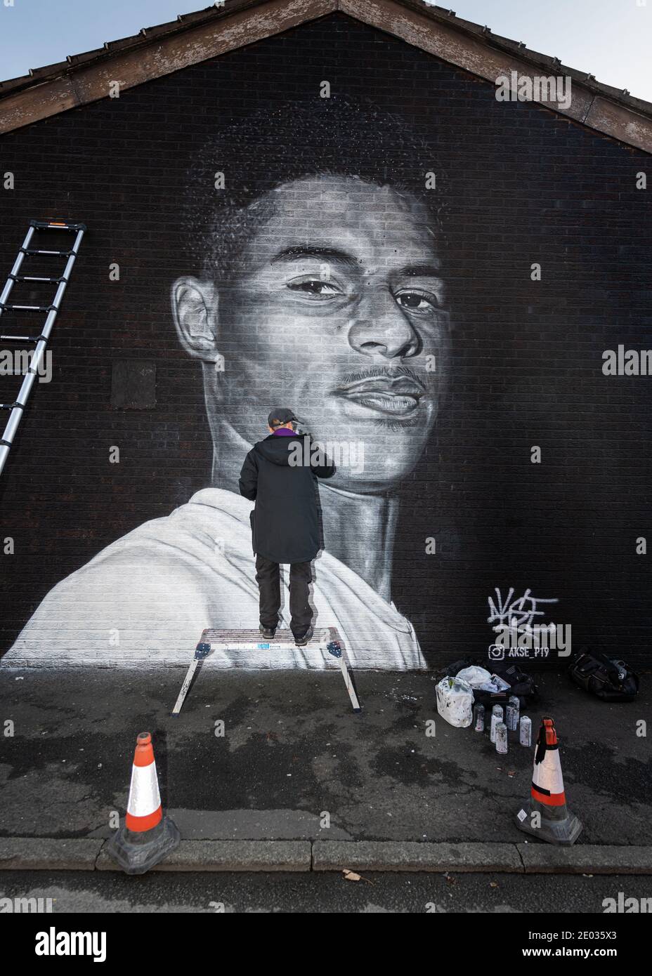Street Artist Akse, steht vor seinem Wandbild des Fußballstars Marcus Rashford. Stockfoto