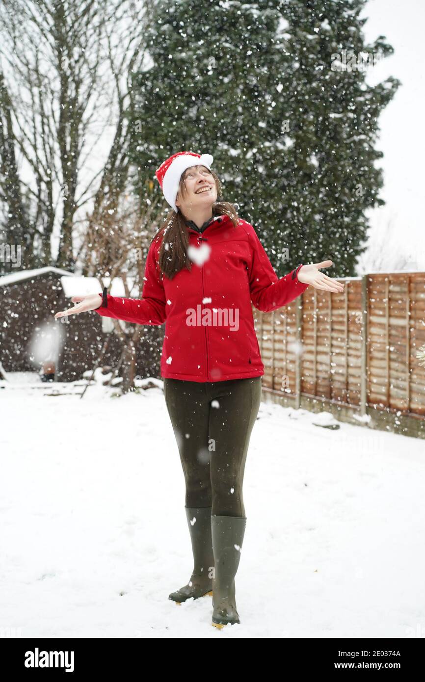 Kidderminster, Großbritannien. Dezember 2020. Wetter in Großbritannien: Während immer mehr Schnee über Worcestershire fällt, weiß diese Frau, wann sie geschlagen wird und gibt fröhlich auf, den Schnee in ihrem Kidderminster Garten zu räumen, um die Wärme im Inneren zu spüren! Eine wunderschöne herzförmige Schneeflocke fällt direkt über sie. Kredit: Lee Hudson/Alamy Live Nachrichten Stockfoto