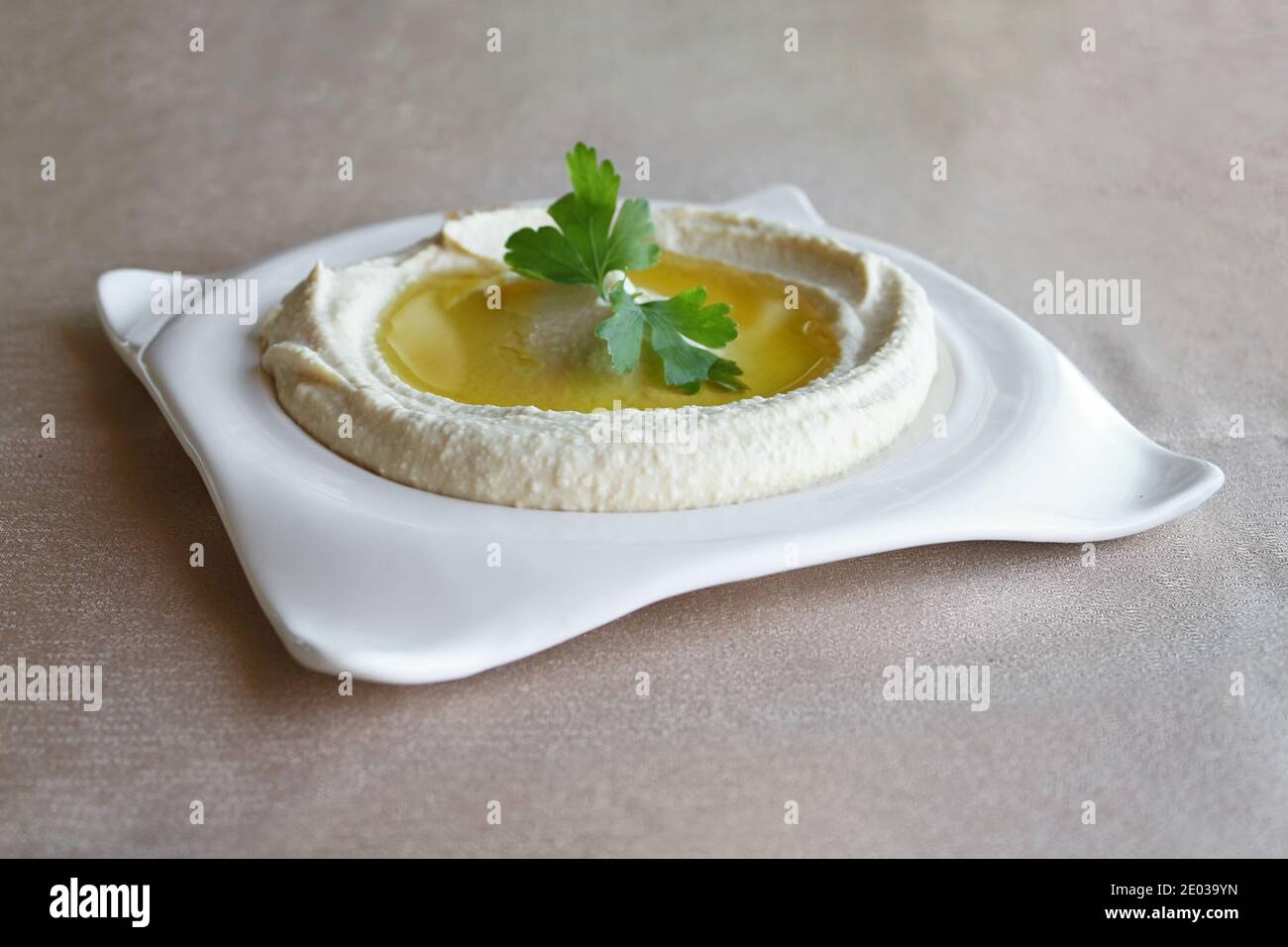 Ein libanesischer traditioneller Hummus-Teller mit viel Olivenöl und einer Petersilie-Garnitur. Stockfoto