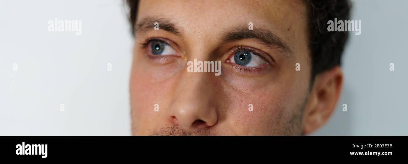 Panoramafoto der blauen Augen eines jungen Mannes mit einem Nachdenklicher Ausdruck auf weißem Hintergrund Stockfoto