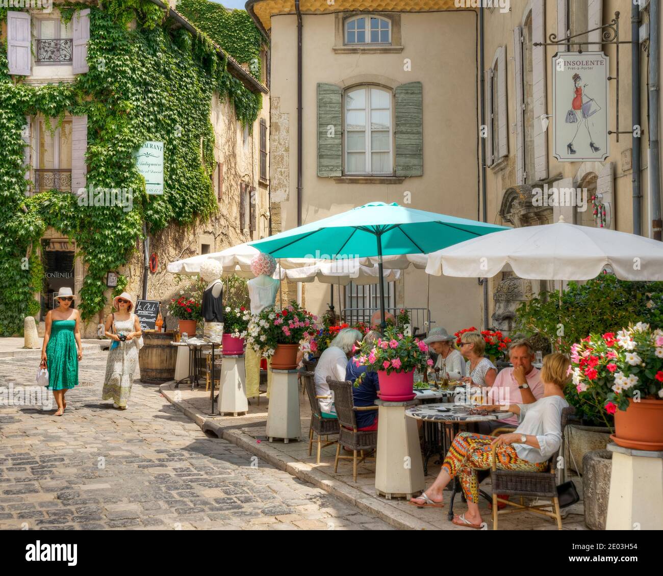 Touristen, die an einem belebten Restaurant im europäischen Stil im Freien in Lourmarin, Provence, Frankreich, vorbeischlendern Stockfoto
