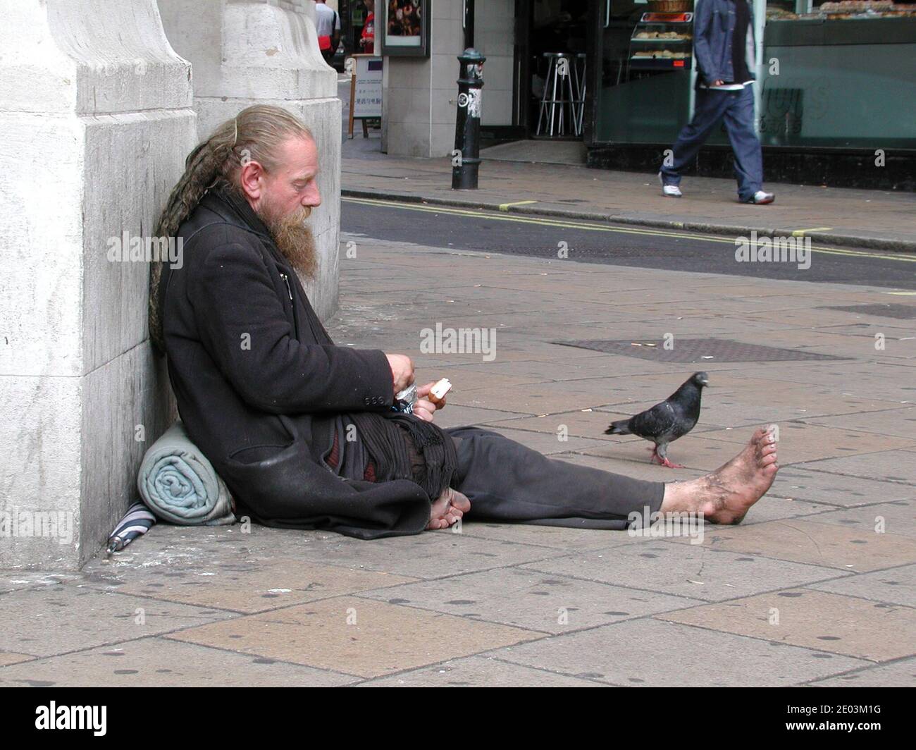 Reiche Arme teilen Ungleichheit, Down and Out obdachlose Landstreicher füttern Tauben auf dem Leicester Square Stockfoto Reiche Arme teilen Ungleichheit, Down and Out obdachlose Landstreicher füttern Tauben auf dem Leicester Square Stockfoto