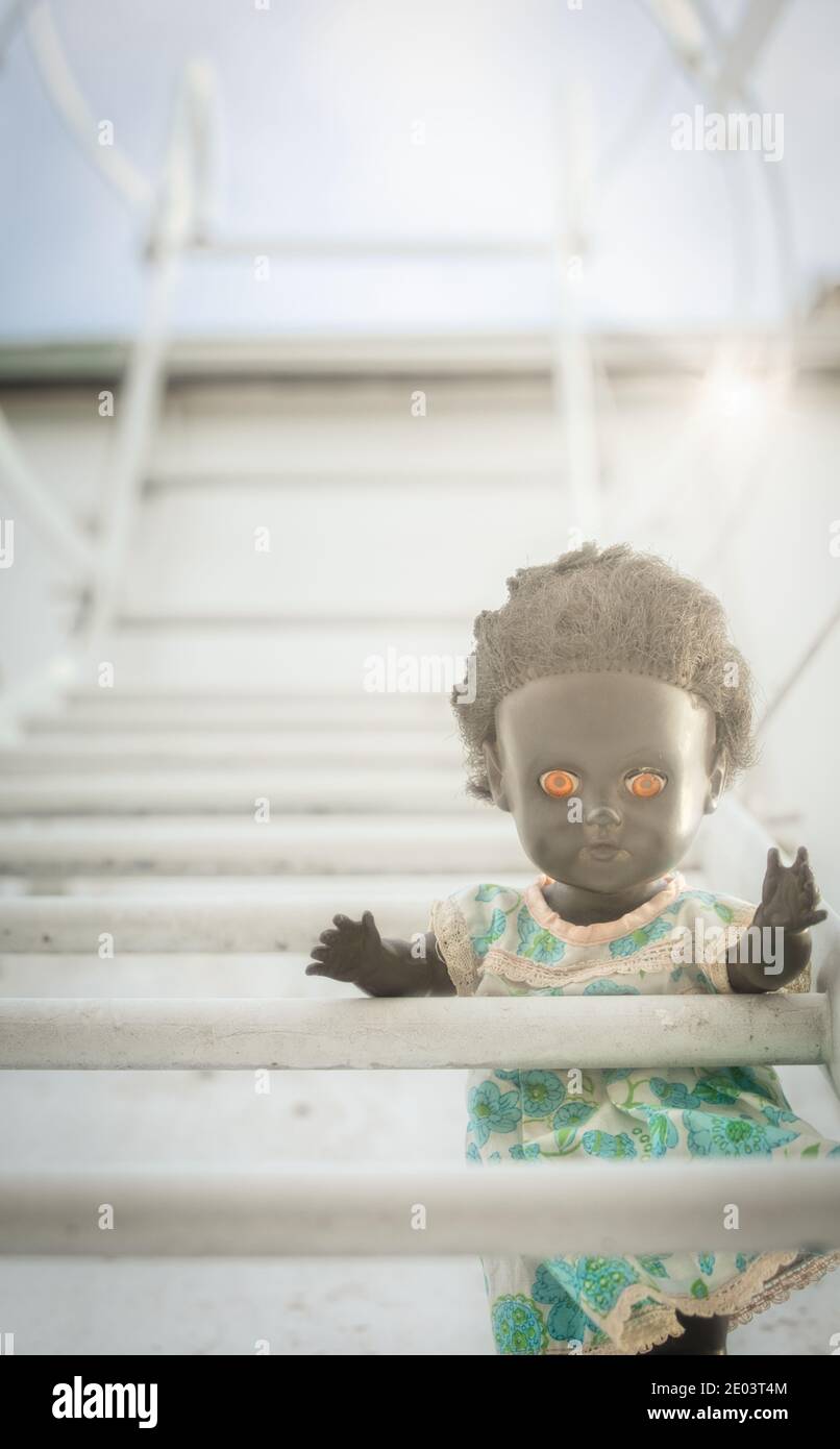 Schwarze Puppe auf Fluchtleiter zum Dach. Konzept von Gefahr, Intrigen und Neugier Stockfoto