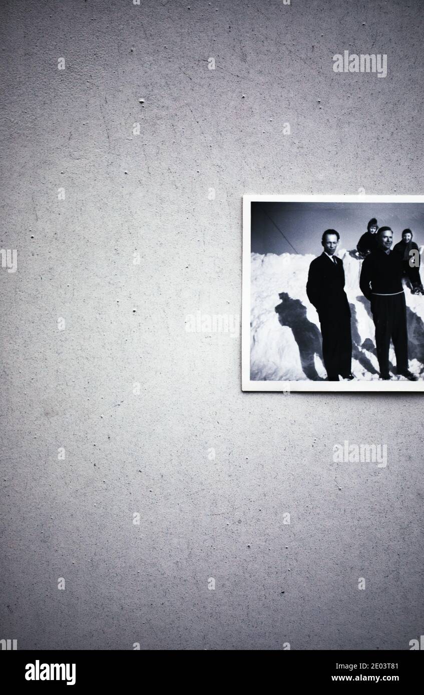 1950 Schwarz-Weiß-Fotografie von vier Personen, die im Schnee, im hellen Sonnenlicht und im Schatten stehen. Stimmungsvolle launische Vintage-Aufnahme im Winter Stockfoto