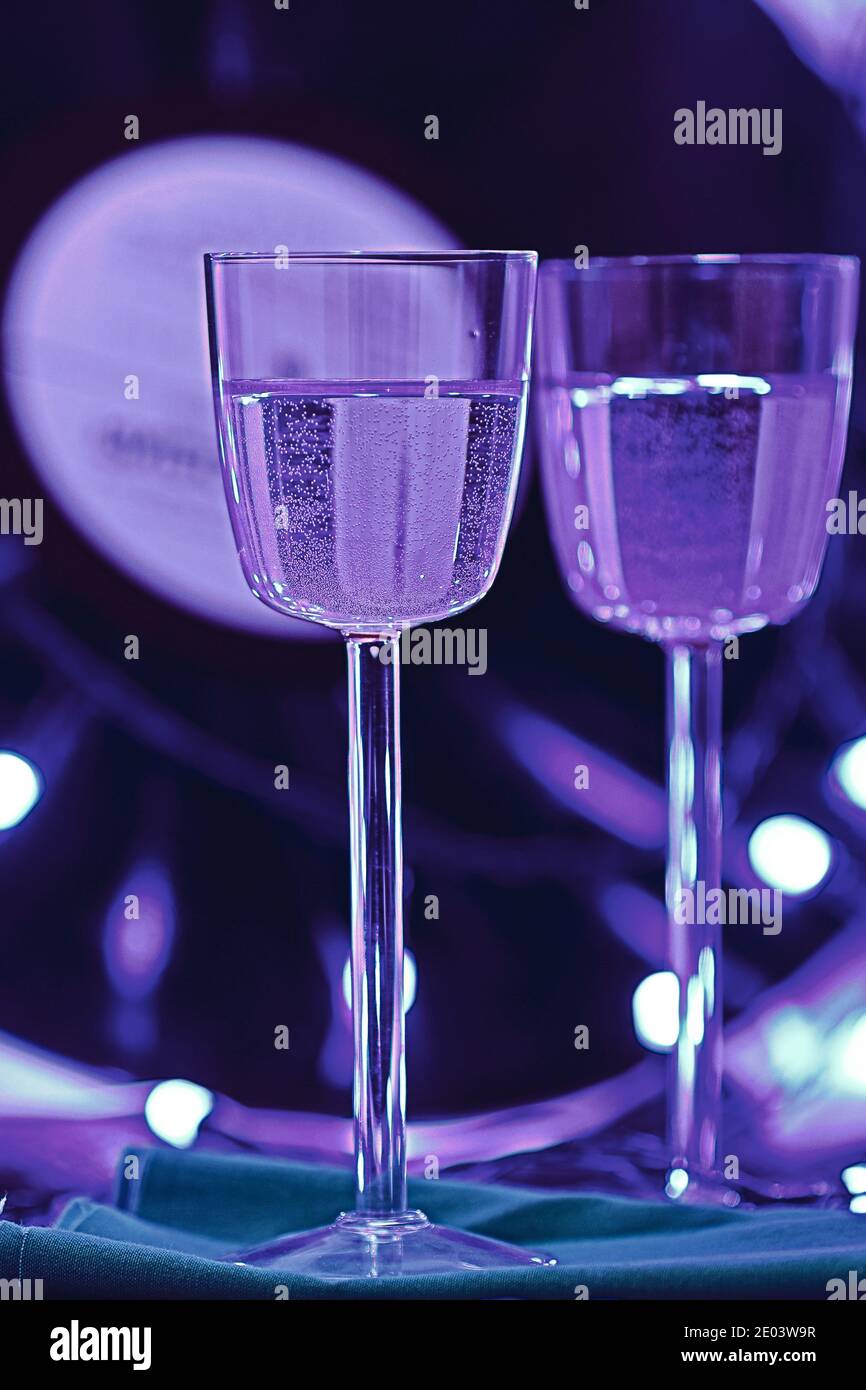 Selektiver Fokus Foto von zwei Gläsern Champagner auf dem Hintergrund einer Vinyl-Platte, umgeben von hellen Club Beleuchtung Stockfoto